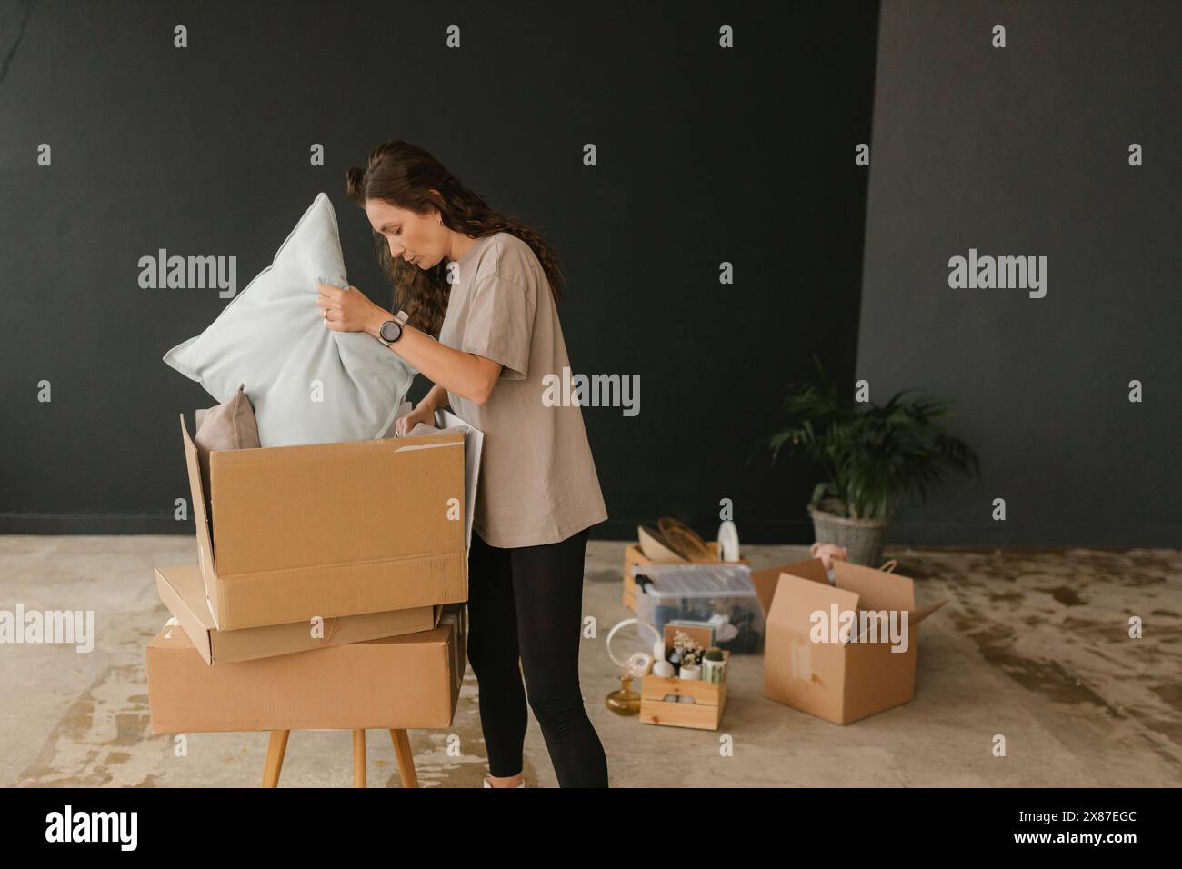 Femme enlevant les coussins de la boîte en carton dans le nouvel appartement Banque D'Images