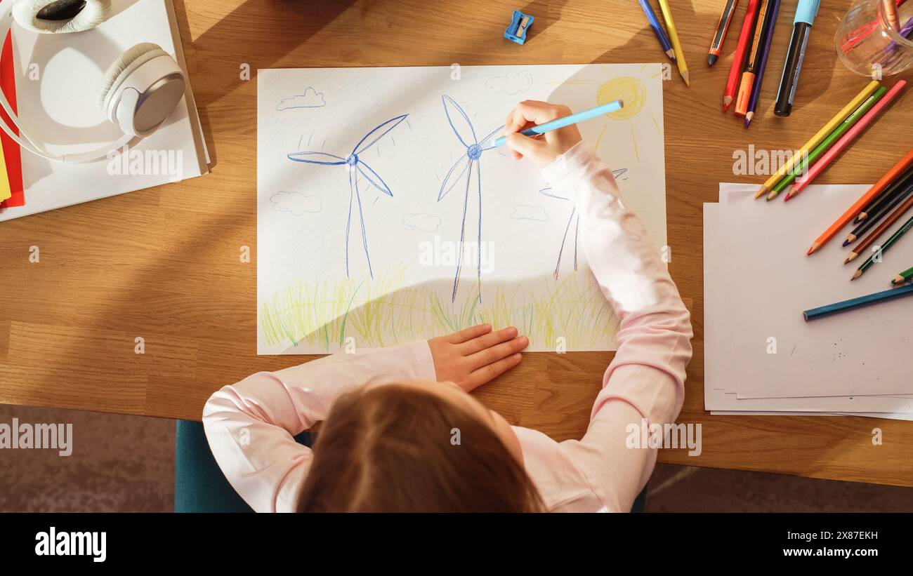 Vue de dessus : petite fille dessinant de belles éoliennes qui ressemblent à des fleurs. À Sunny Day Smart Talented Child imaginant notre planète comme un endroit heureux avec une énergie verte propre et durable pour tout le monde Banque D'Images