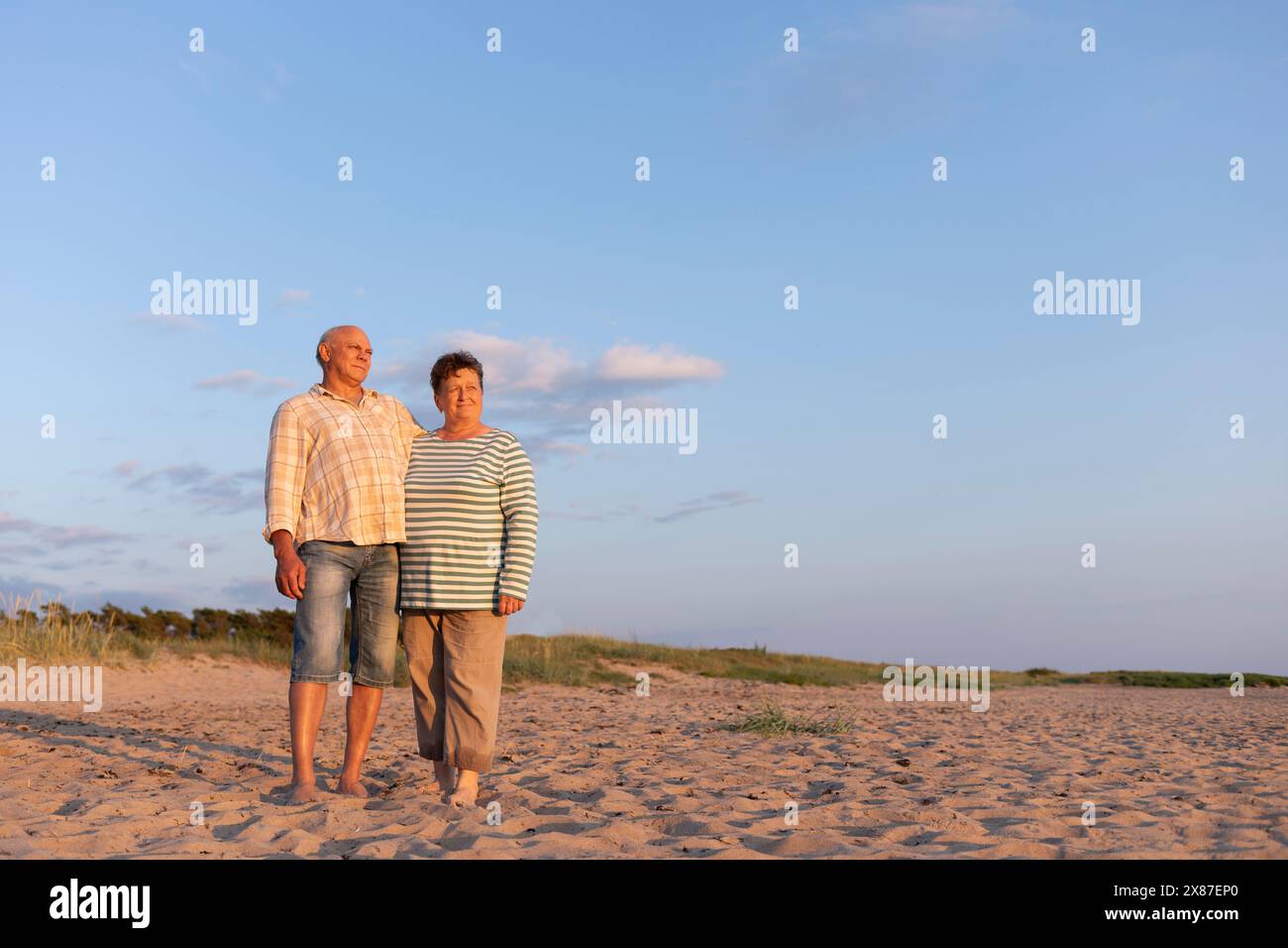 Couple debout à la plage sous le ciel au coucher du soleil Banque D'Images