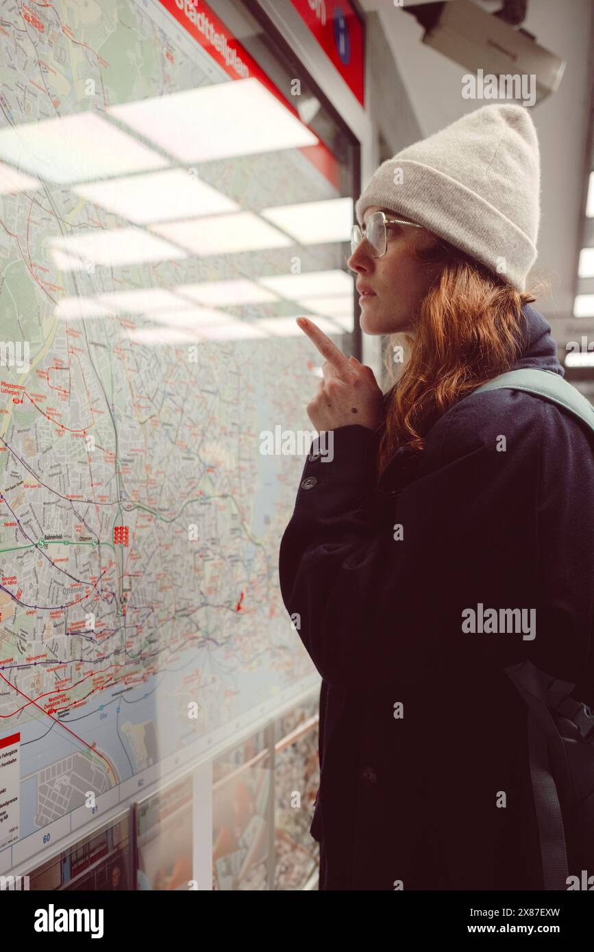 Femme rousse examinant la carte routière ferroviaire à la gare Banque D'Images