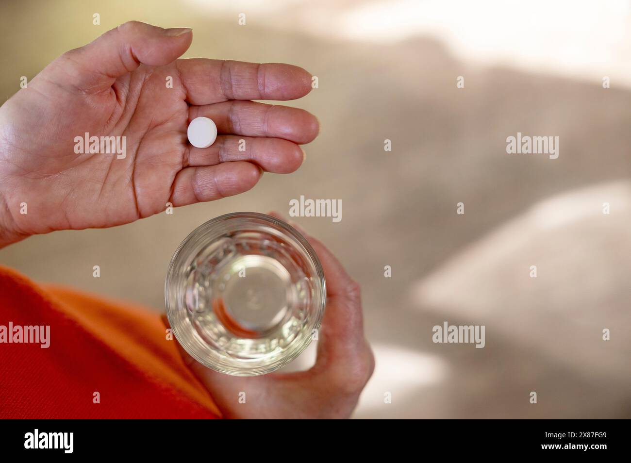 Femme tenant un verre d'eau avec la pilule à la main à la maison Banque D'Images