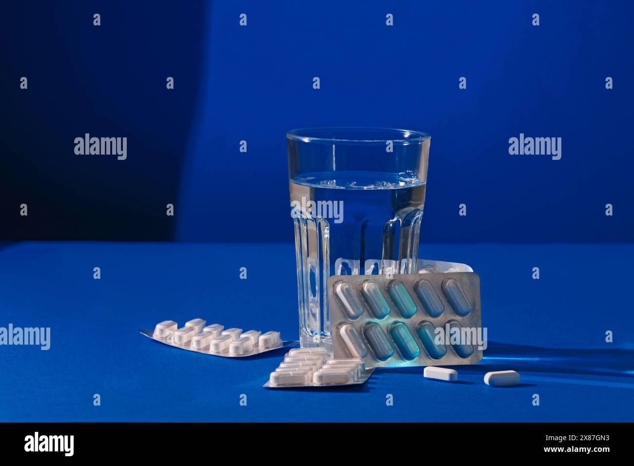 Verre d'eau avec des médicaments sur fond bleu Banque D'Images