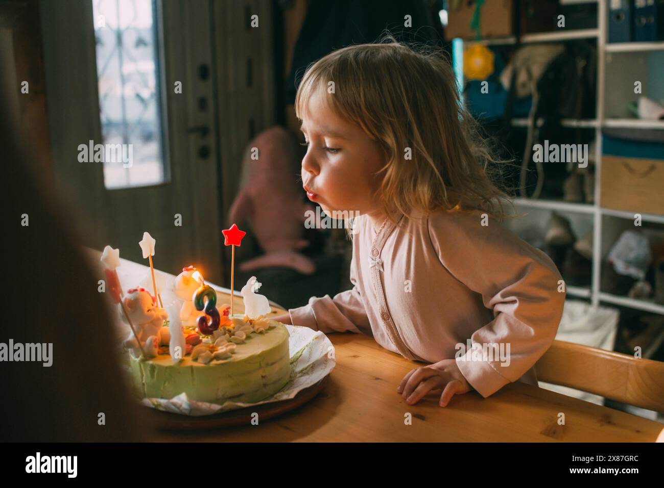 Fille soufflant la bougie sur le gâteau d'anniversaire à la maison Banque D'Images