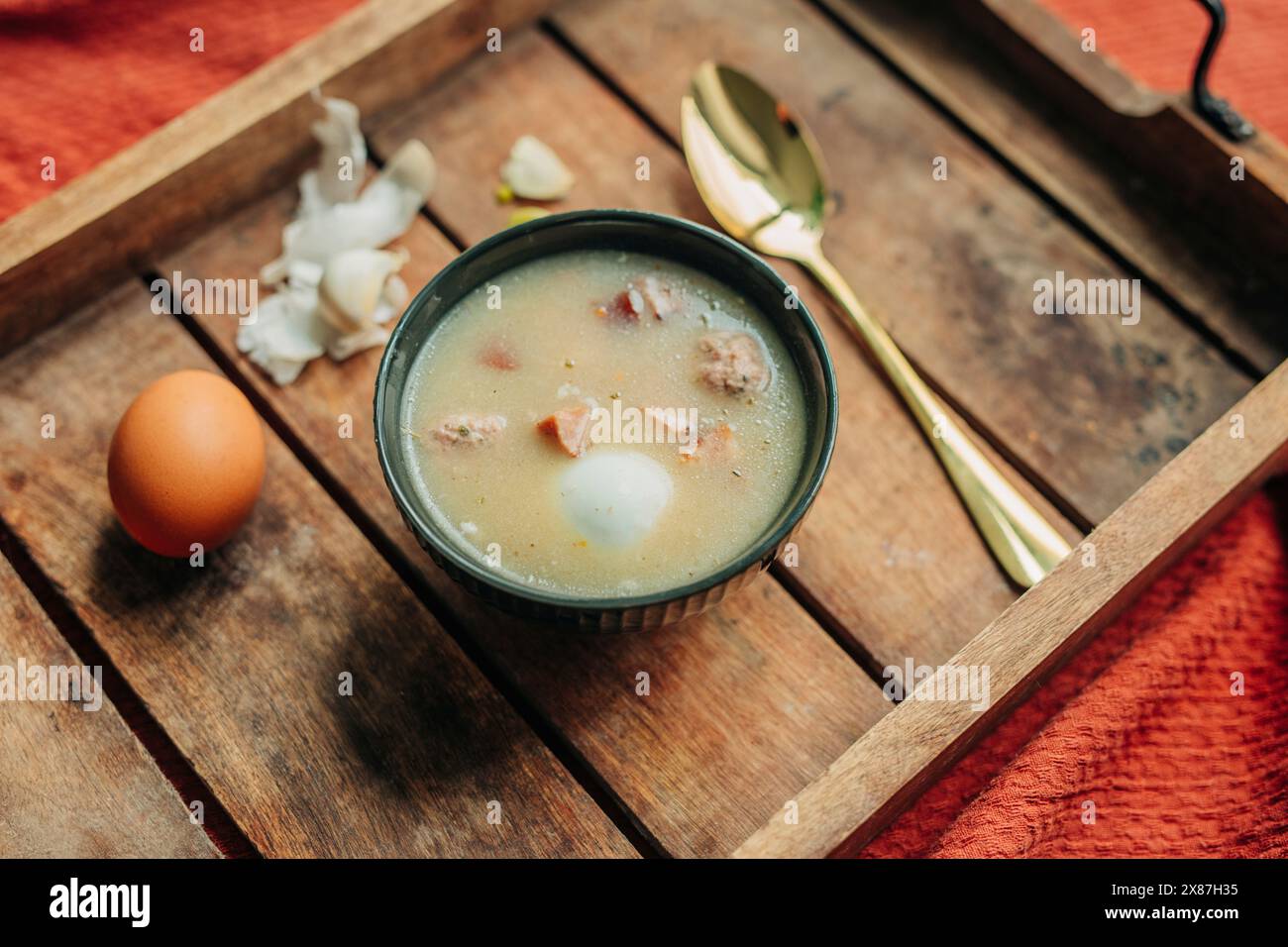Soupe polonaise traditionnelle fraîche Zurek dans un bol sur un plateau en bois Banque D'Images