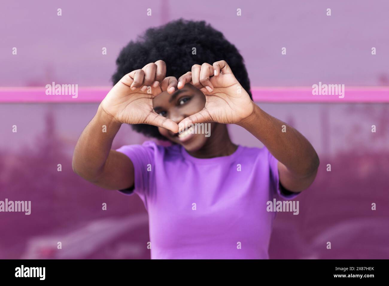 Jeune femme souriante montrant la forme de coeur avec les mains Banque D'Images