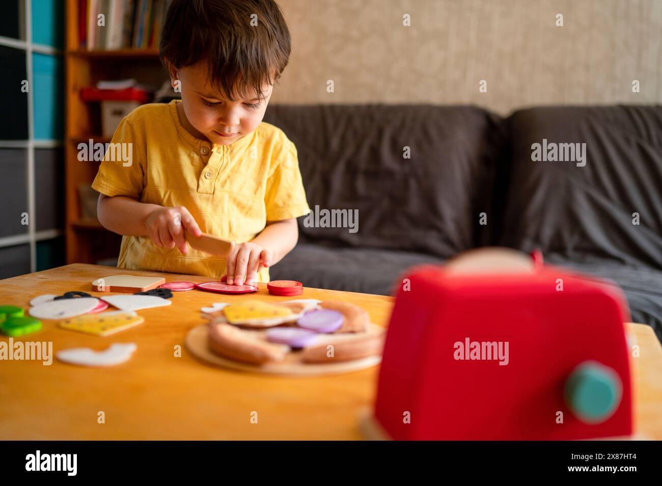 Garçon jouant à un jeu de cuisine avec une cuisine jouet à la maison Banque D'Images