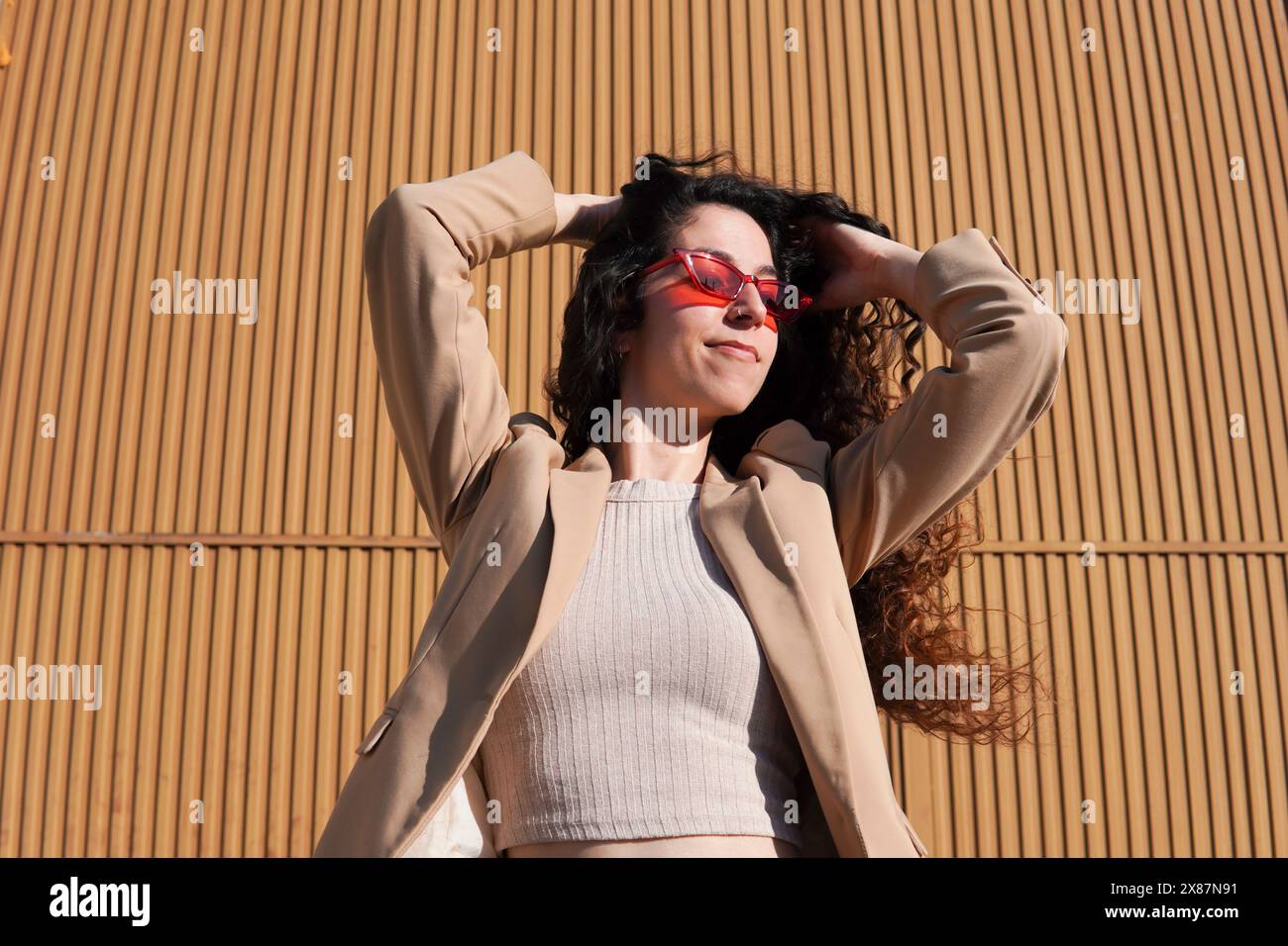 Femme aux cheveux bouclés portant des lunettes de soleil rouges le jour ensoleillé Banque D'Images