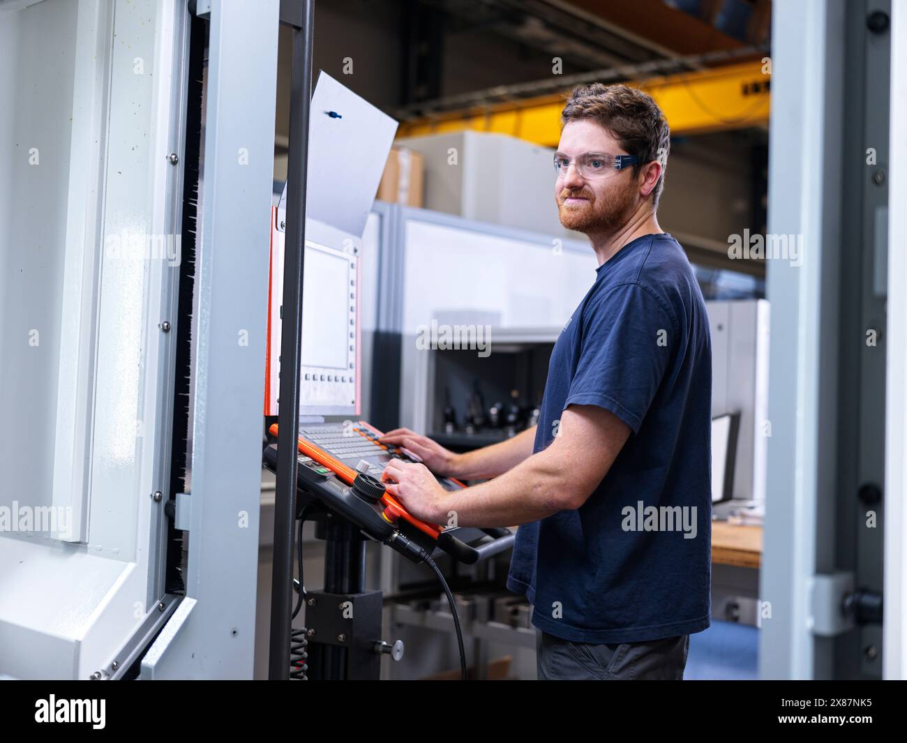 Apprenti ingénieur exploitant la machine CNC en usine Banque D'Images