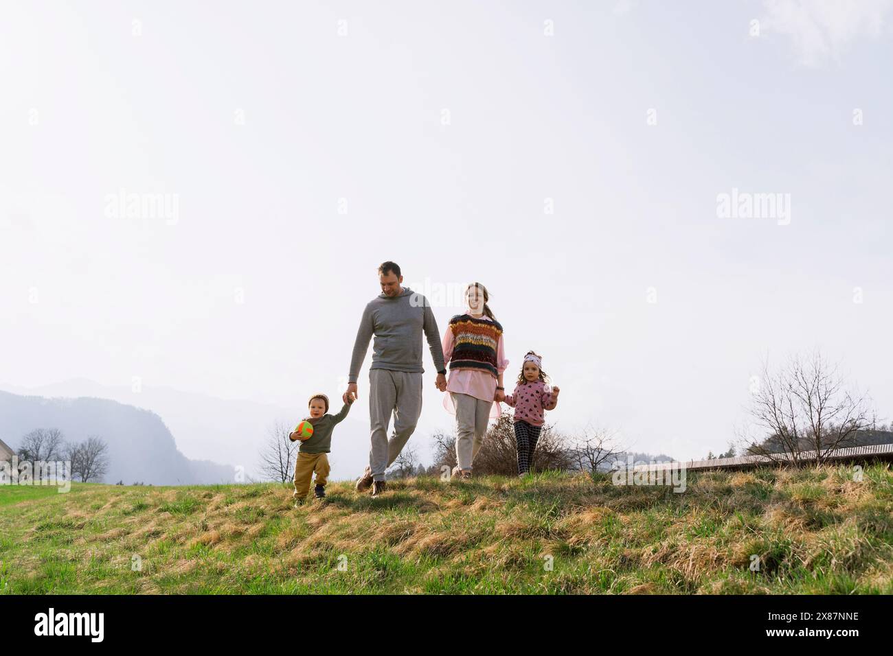 Mère et père marchant avec les enfants sur l'herbe au soleil Banque D'Images Mère et père marchant avec les enfants sur l'herbe au soleil Banque D'Images