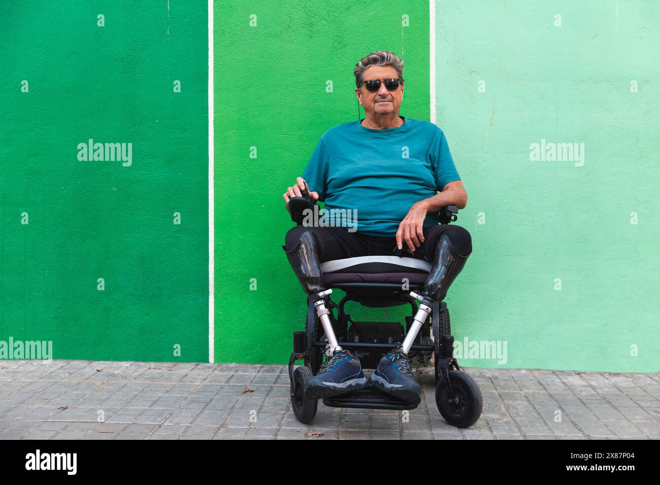 Homme senior en fauteuil roulant motorisé devant le mur vert Banque D'Images Homme senior en fauteuil roulant motorisé devant le mur vert Banque D'Images