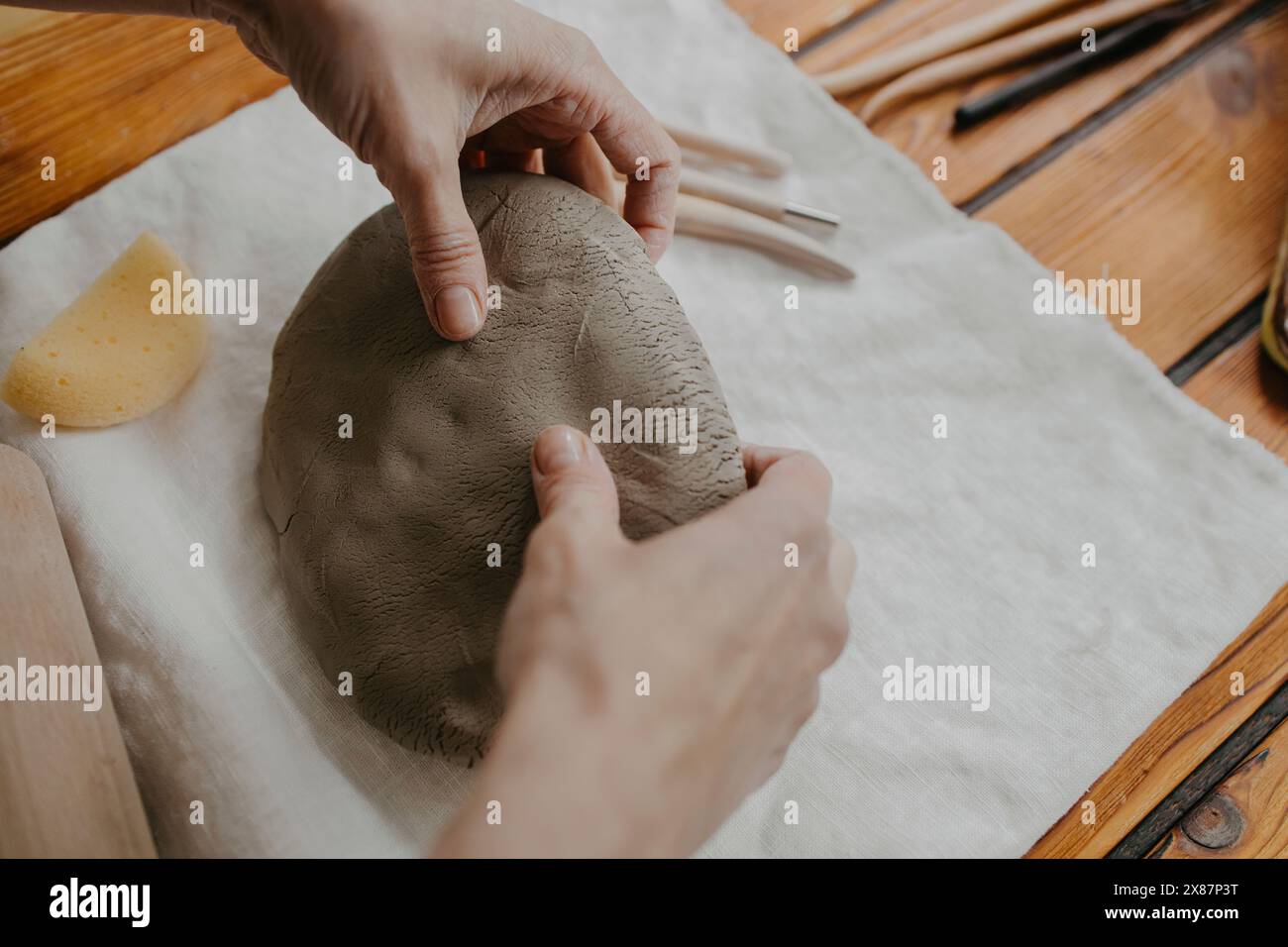 Mains de femme façonnant de l'argile sur tissu blanc Banque D'Images