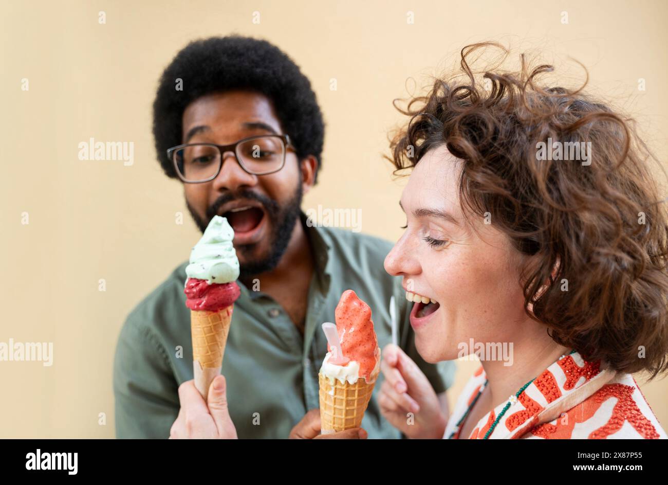 Heureux amis partageant la crème glacée devant le mur Banque D'Images Heureux amis partageant la crème glacée devant le mur Banque D'Images