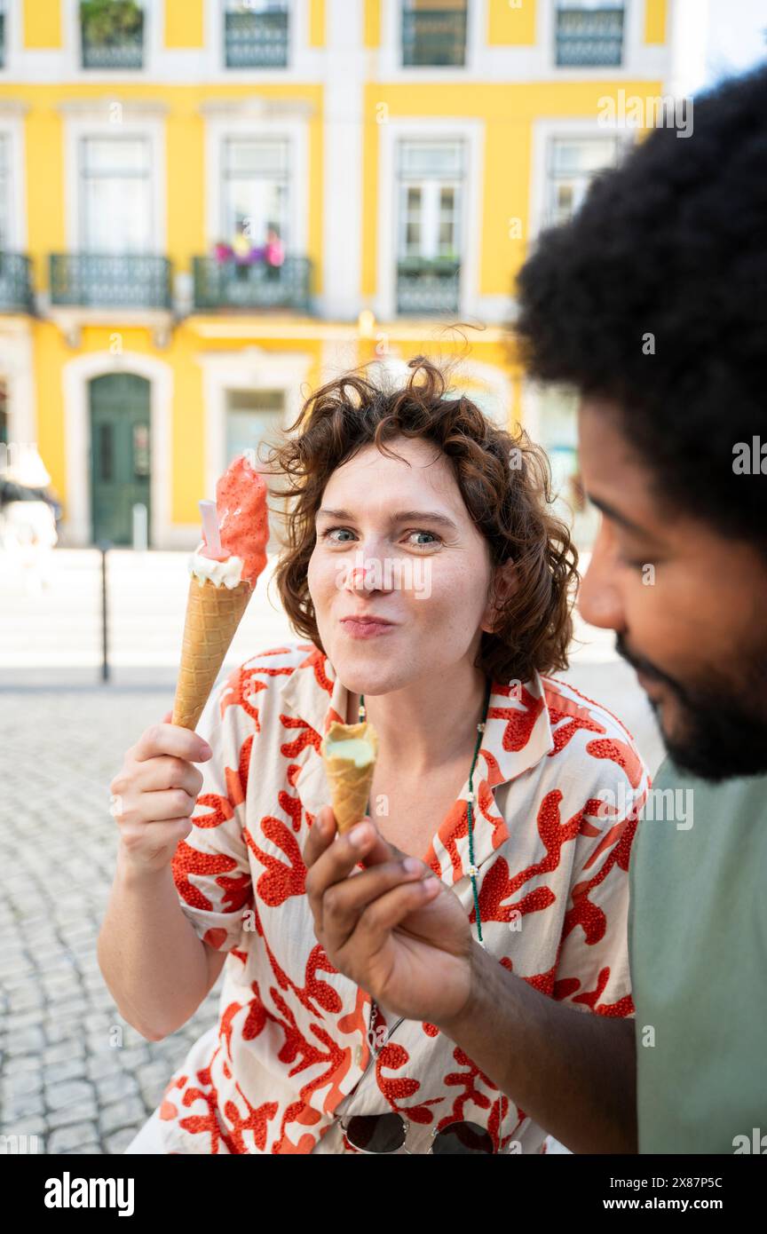 Femme joueuse mangeant de la crème glacée avec un ami dans la rue Banque D'Images Femme joueuse mangeant de la crème glacée avec un ami dans la rue Banque D'Images