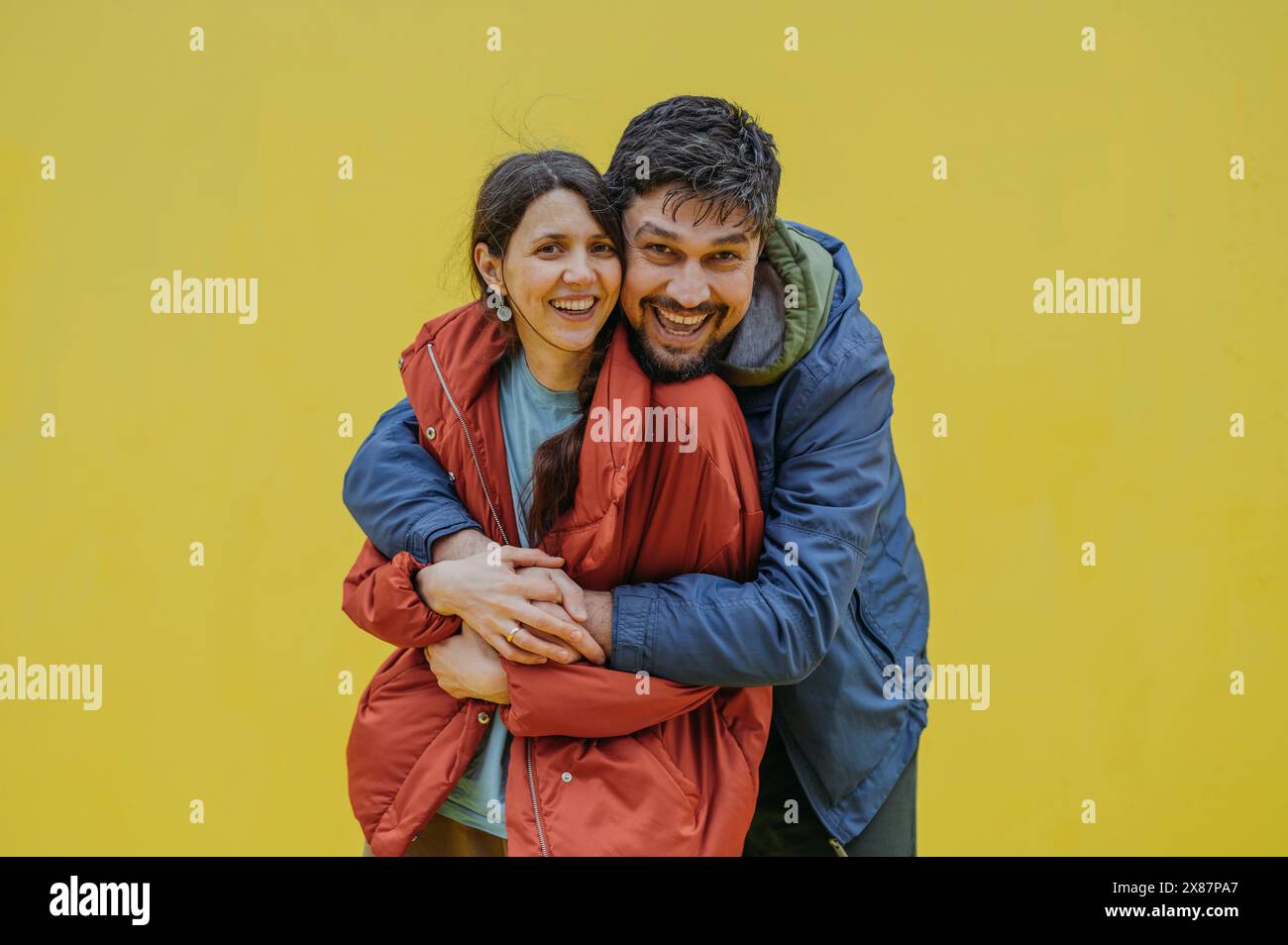 Homme mûr heureux embrassant la femme sur fond jaune Banque D'Images Homme mûr heureux embrassant la femme sur fond jaune Banque D'Images