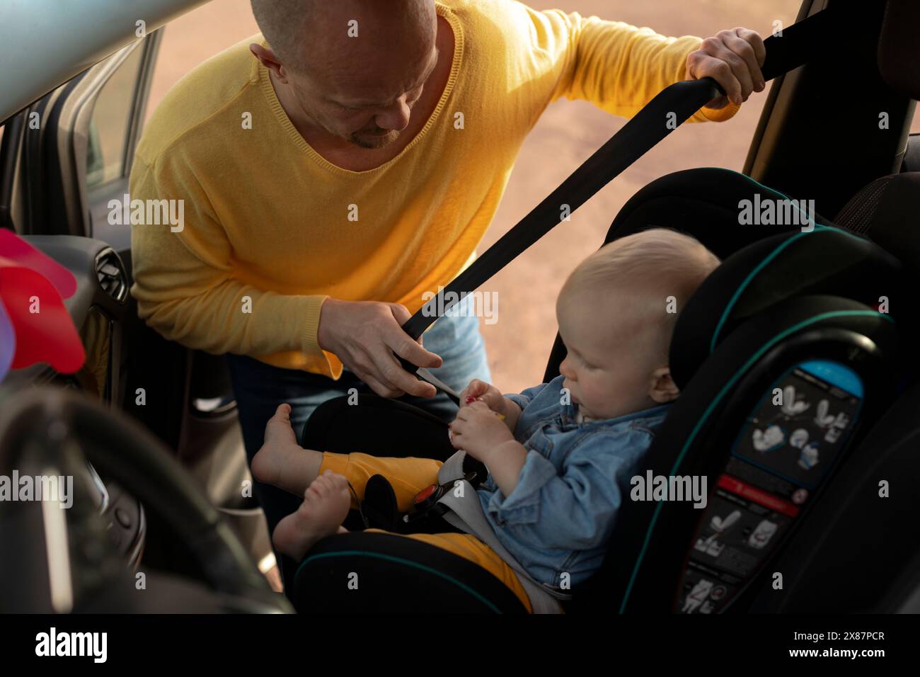 Homme attachant la ceinture de sécurité pour fils dans la voiture Banque D'Images Homme attachant la ceinture de sécurité pour fils dans la voiture Banque D'Images
