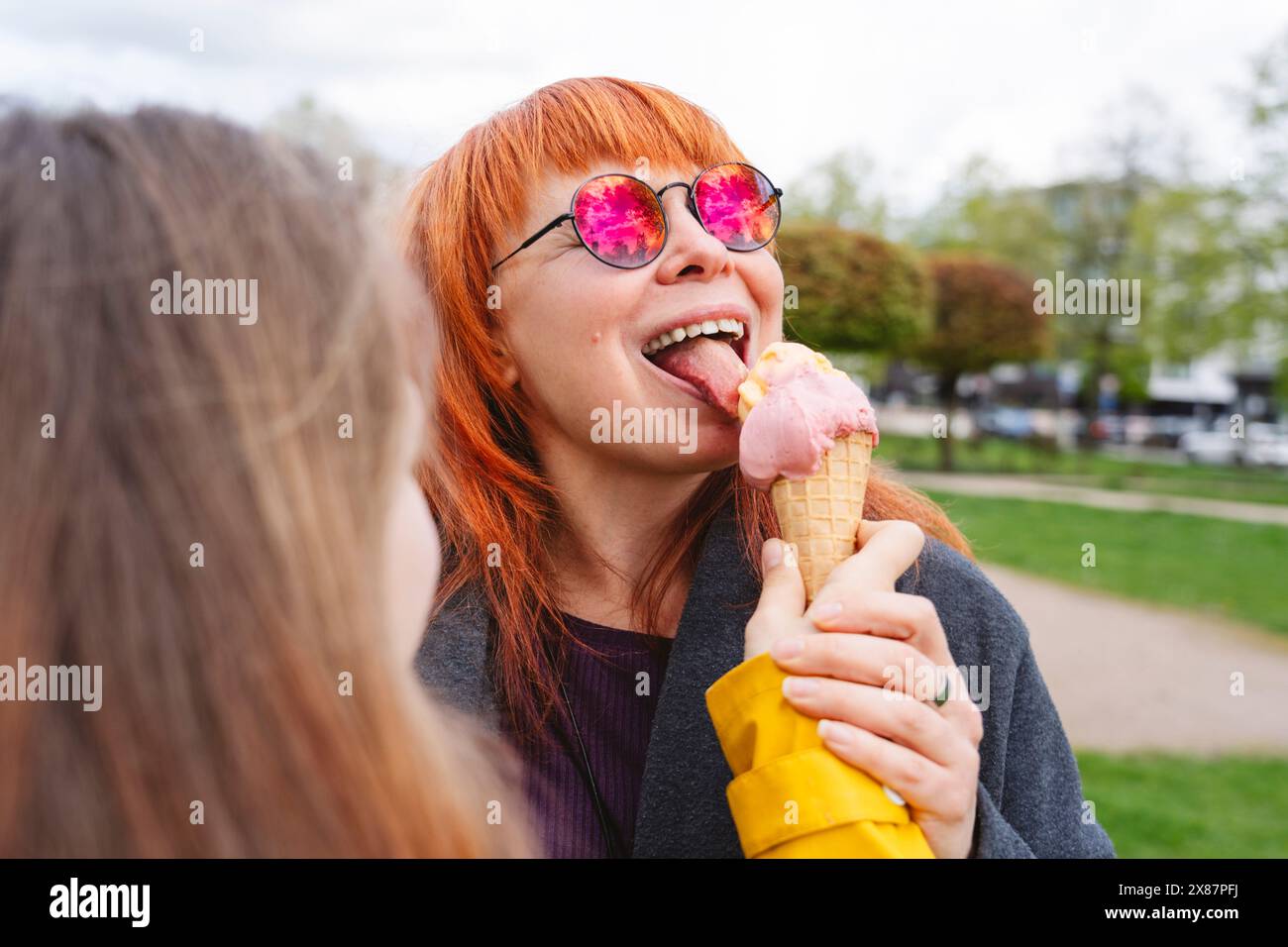 Fille nourrissant la crème glacée à la mère au parc Banque D'Images