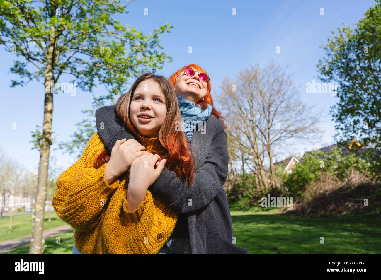 Heureuse mère embrassant sa fille un jour ensoleillé au parc Banque D'Images Heureuse mère embrassant sa fille un jour ensoleillé au parc Banque D'Images