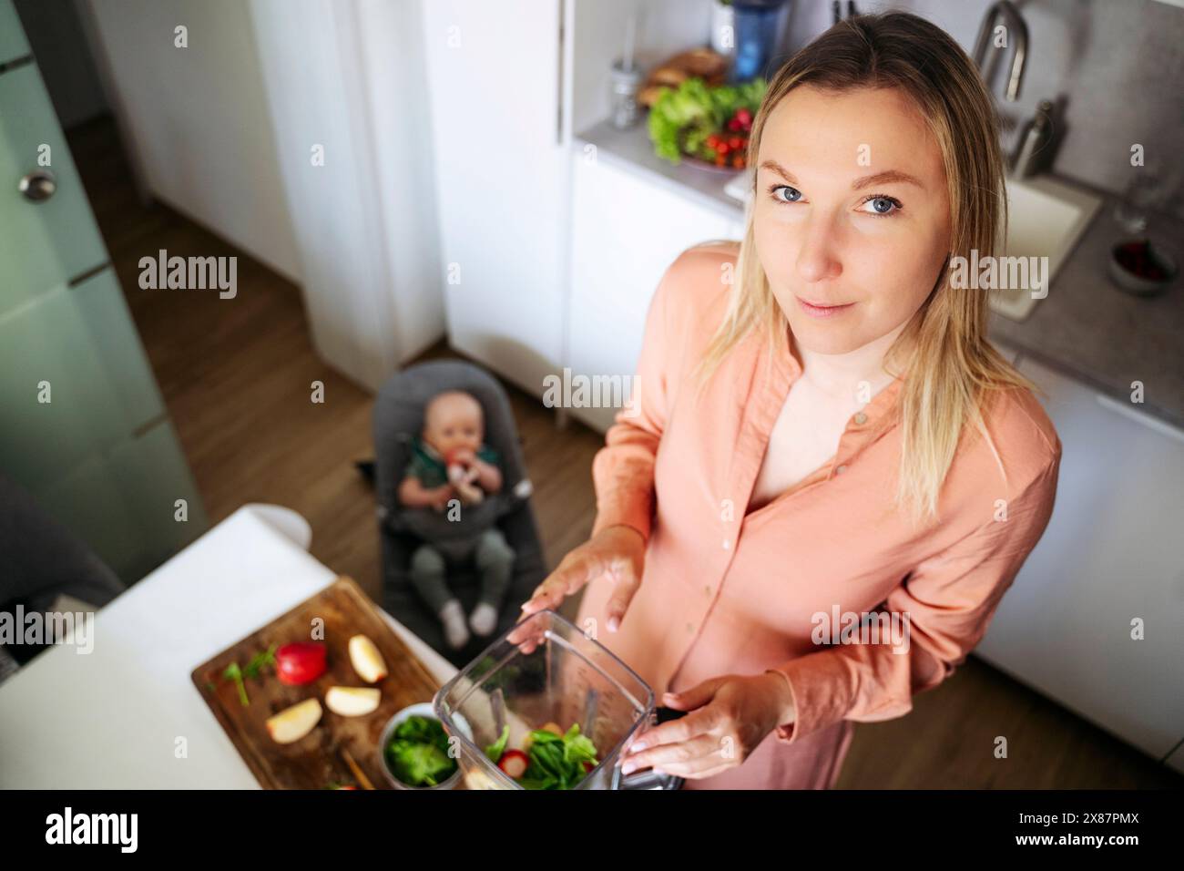Femme blonde faisant un smoothie aux fruits dans un blender à la maison Banque D'Images Femme blonde faisant un smoothie aux fruits dans un blender à la maison Banque D'Images