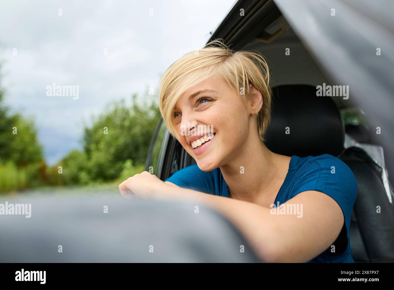 Heureuse jeune femme regardant par la fenêtre assise dans la voiture Banque D'Images Heureuse jeune femme regardant par la fenêtre assise dans la voiture Banque D'Images