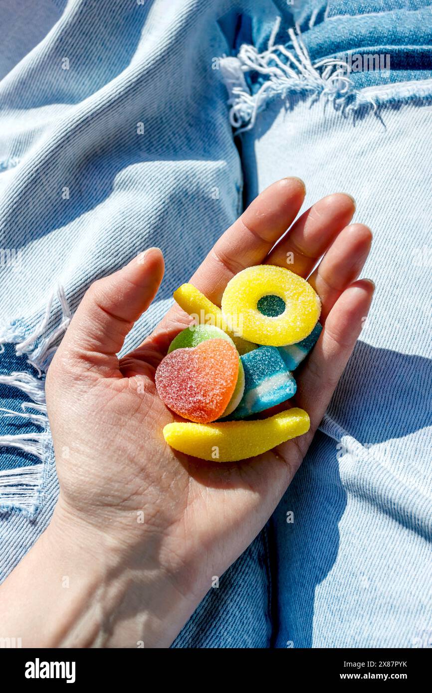 Main de femme tenant des bonbons gelés sur un Jean bleu Banque D'Images