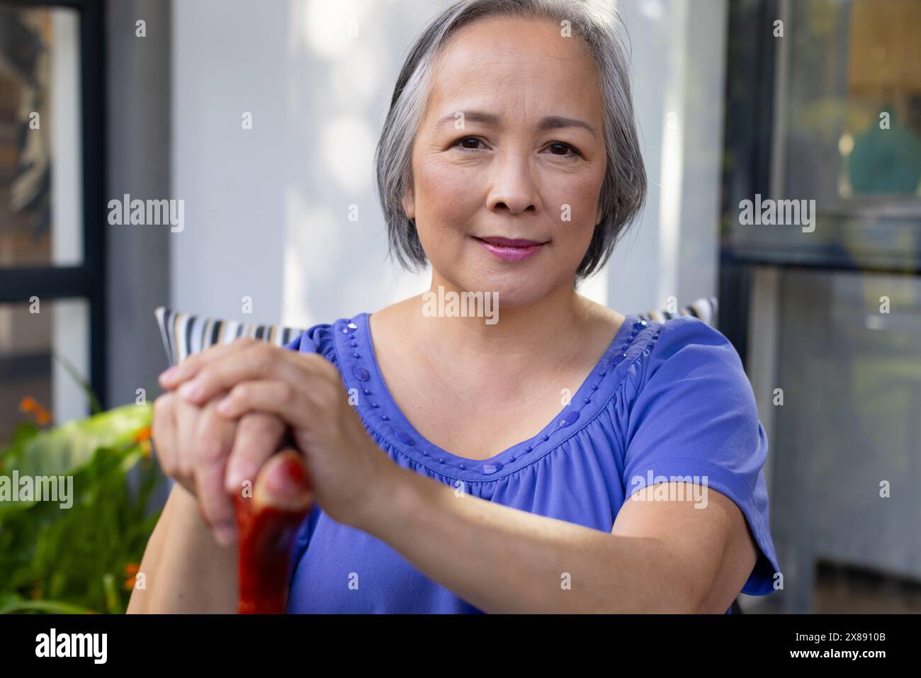 À l'extérieur, femelle asiatique d'âge moyen en haut bleu, tenant une canne Banque D'Images