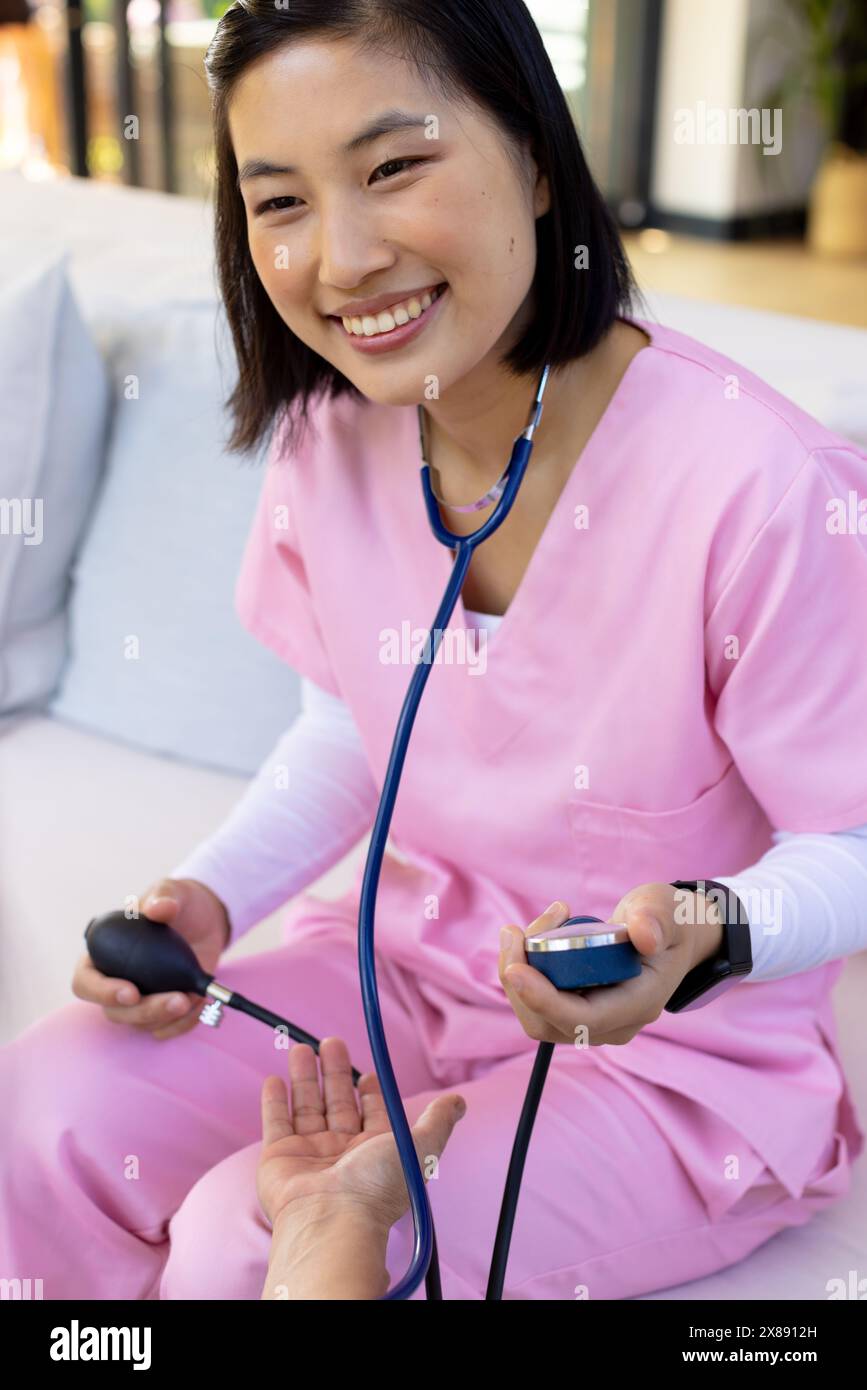 Une infirmière asiatique et un patient d'âge moyen vérifient la pression artérielle à domicile Banque D'Images