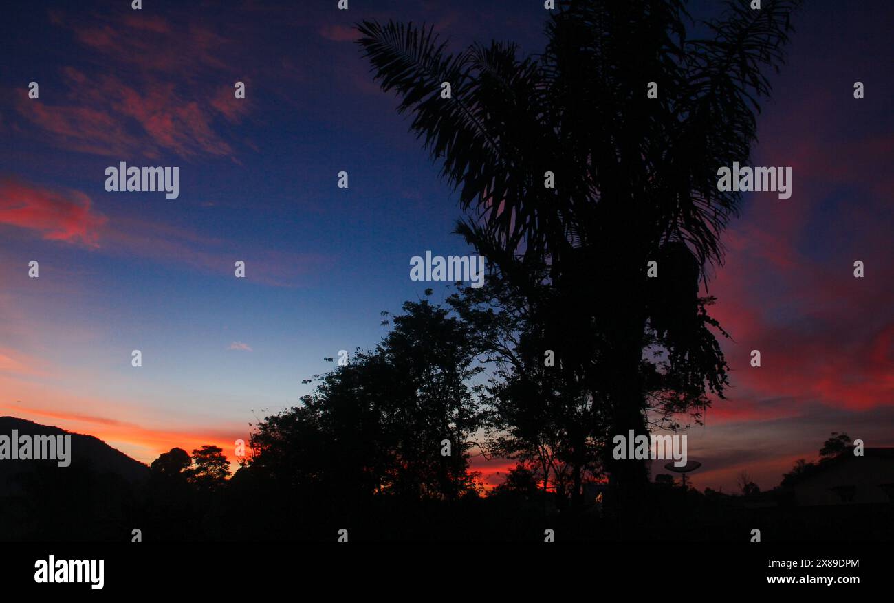 Les levers de soleil dans une montagne avec des silhouettes de collines et plusieurs arbres qui poussent habituellement dans les forêts tropicales humides Banque D'Images