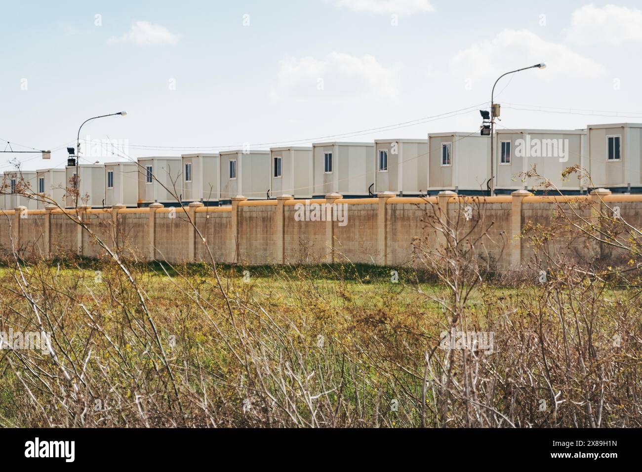 Unités de logement de conteneurs derrière un mur au Ħal Far Open Centre, un centre de logement pour migrants et demandeurs d'asile à Malte Banque D'Images Unités de logement de conteneurs derrière un mur au Ħal Far Open Centre, un centre de logement pour migrants et demandeurs d'asile à Malte Banque D'Images