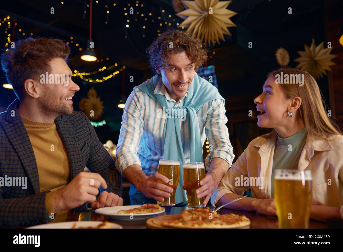Vue rapprochée d'un gars joyeux achetant de la bière à des amis pendant le repos au bar Banque D'Images