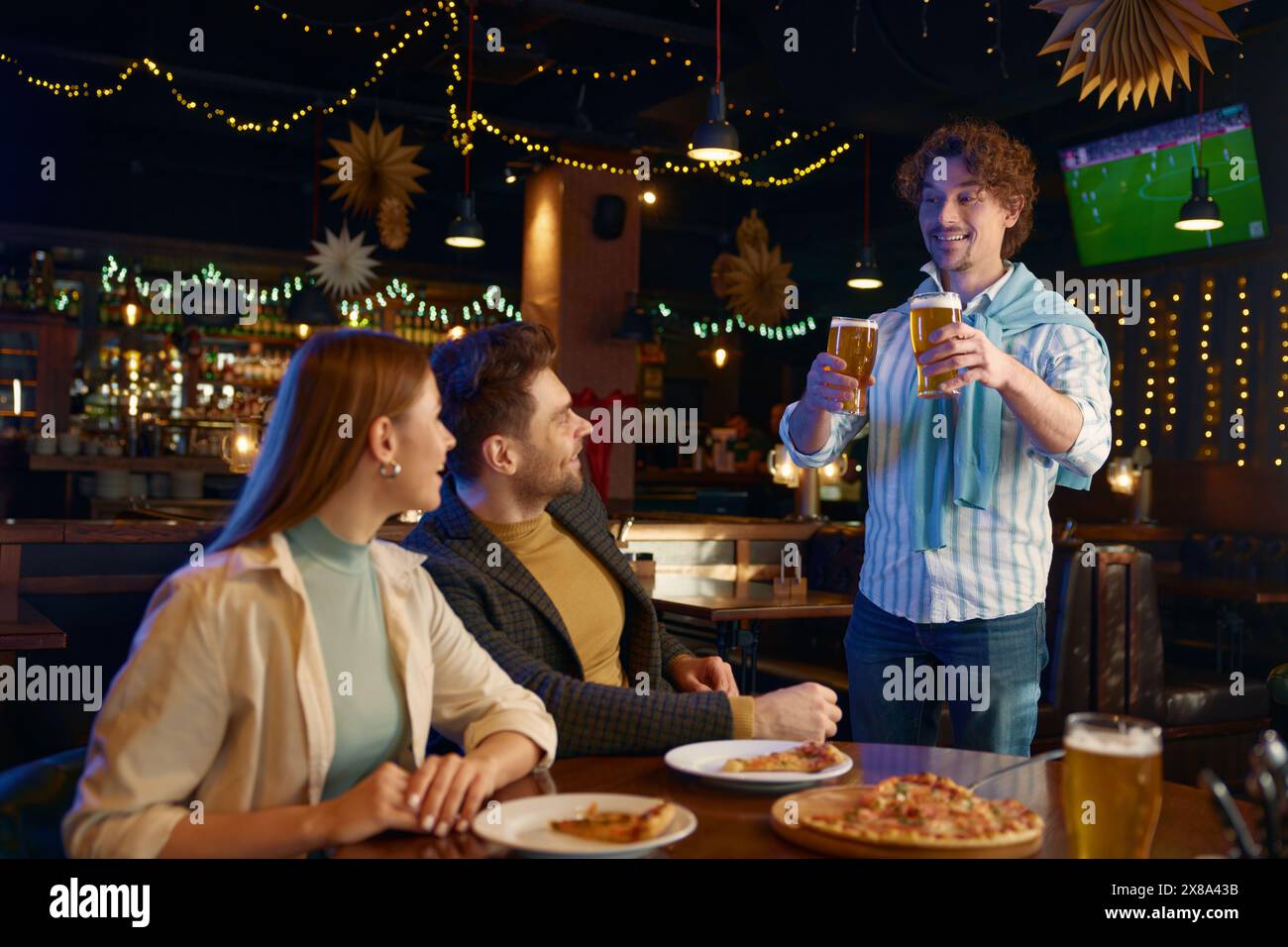 Gars joyeux achetant de la bière d'amis pendant le repos dans le bar Banque D'Images