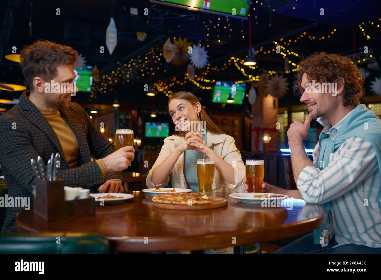 Amis mangeant de la pizza buvant de la bière pendant le repos dans un pub Banque D'Images