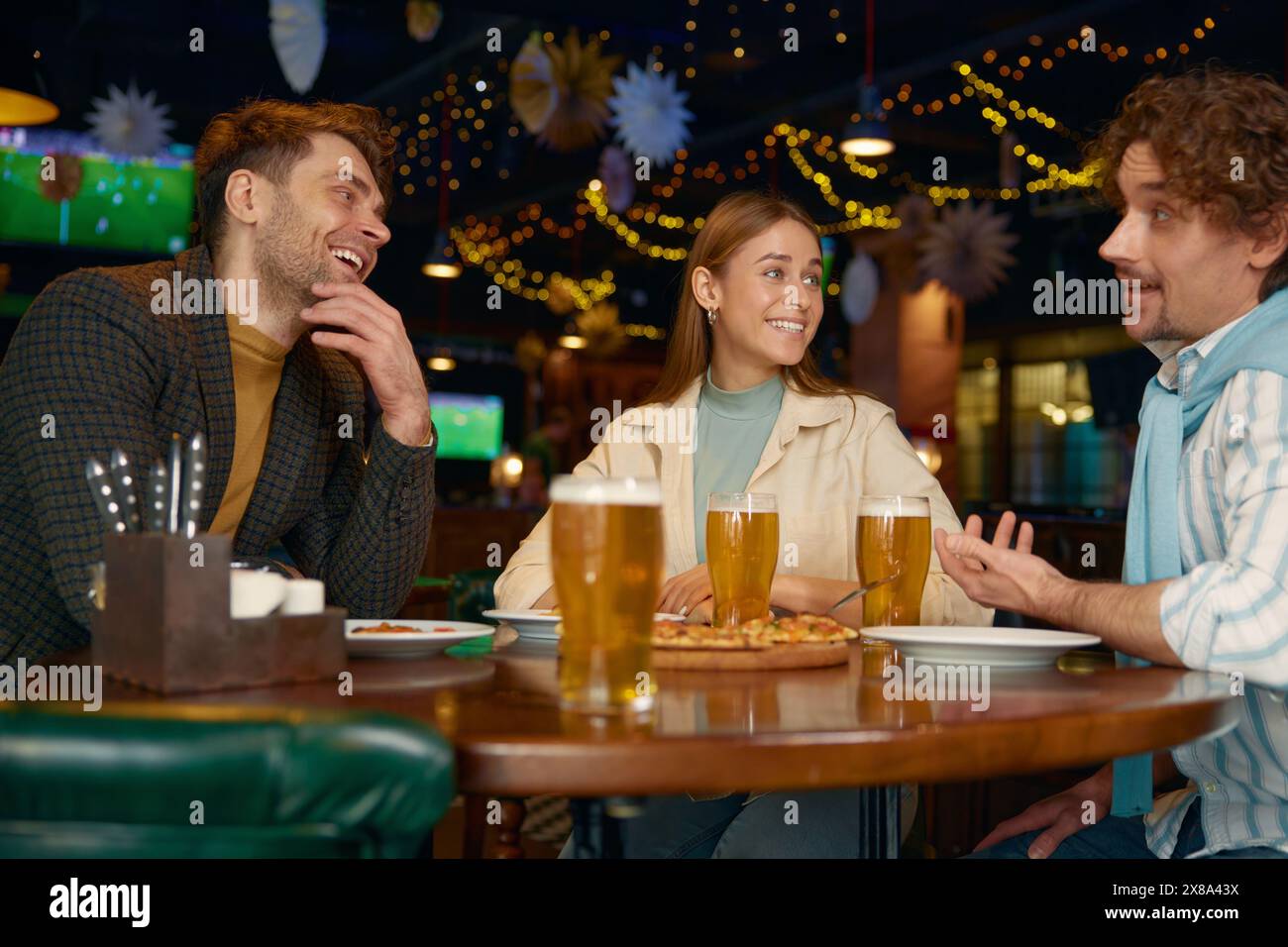 Jeunes amis mangeant de la pizza buvant de la bière pendant le repos dans un pub Banque D'Images