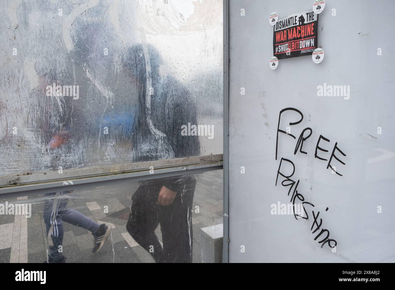 Graffiti et affiche gratuits pour la Palestine dans un abri de bus à Dumfries, en Écosse, un jour de pluie avec des gens qui passent devant. Banque D'Images
