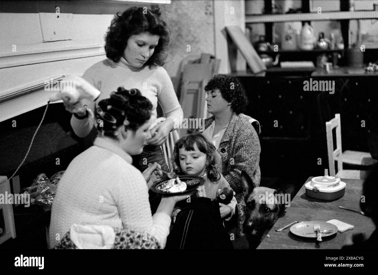 Le refuge pour femmes battues, une échappatoire à la violence domestique. Il y avait une politique de la porte ouverte à Chiswick Women’s Aid ; les femmes victimes d’abus pouvaient simplement se présenter. Ils sont venus avec leurs enfants souvent dérangés et ont parfois été eux-mêmes mentalement endommagés. La communauté offrait un environnement où les femmes vivant dans des circonstances semblables pouvaient apporter un soutien affectif et moral ainsi que de l'amitié. Une famille et leur chien de compagnie. Richmond, Londres, Angleterre vers novembre 1975. 1970S UK HOMER SYKES Banque D'Images