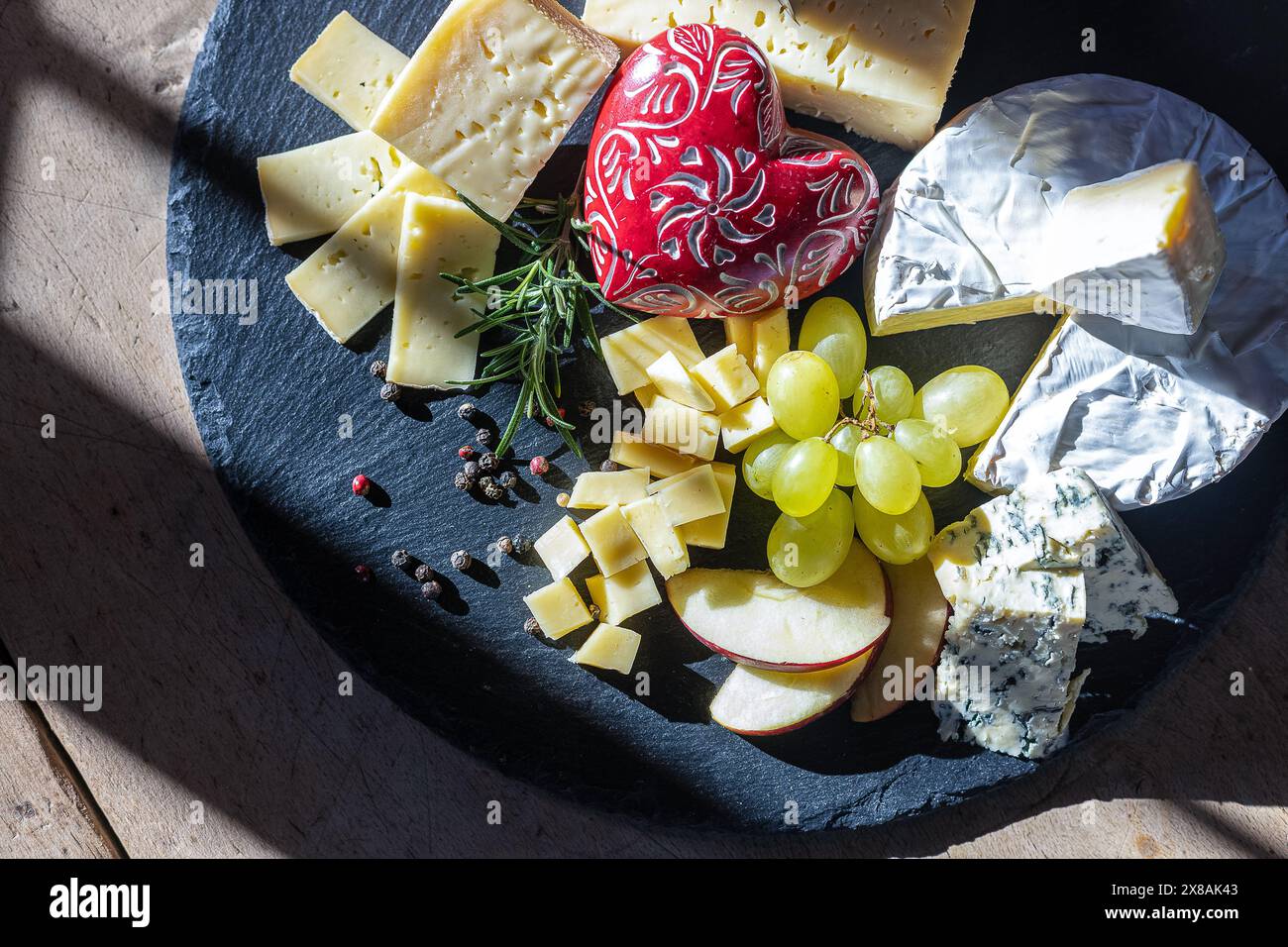 Plateau de fromage avec raisins, tranches de pommes et un coeur décoratif Banque D'Images