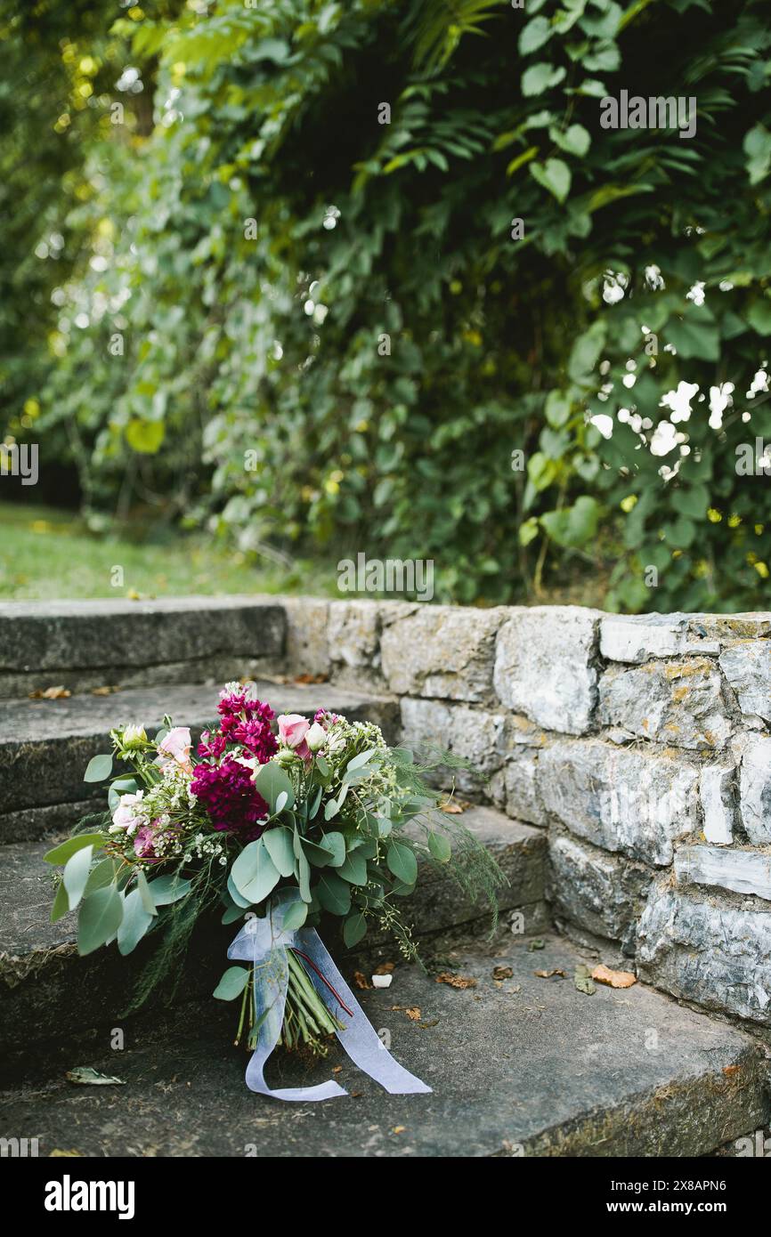 Le bouquet de mariée de mariage repose sur des marches en pierre avec des fleurs roses Banque D'Images