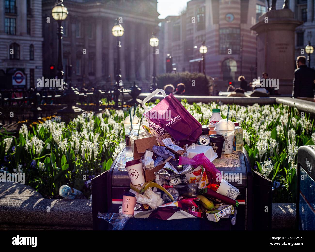 Une poubelle débordante au cœur de la City de Londres. Boites de boisson, tasses à café, bouteilles en plastique, cartons et ordures générales. Drame fort contre-jour Banque D'Images