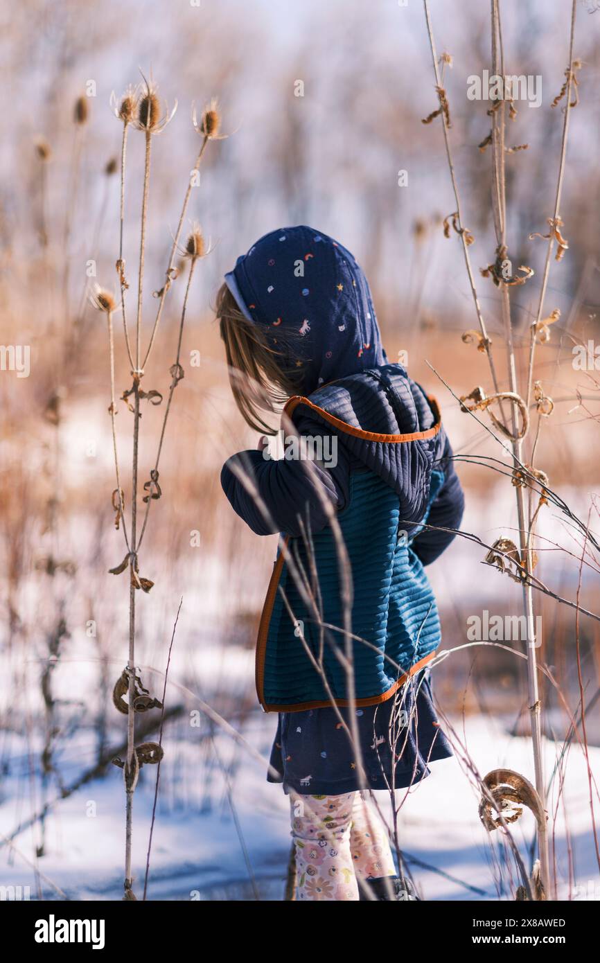 Enfant explorant la nature hivernale dans une clairière forestière Banque D'Images