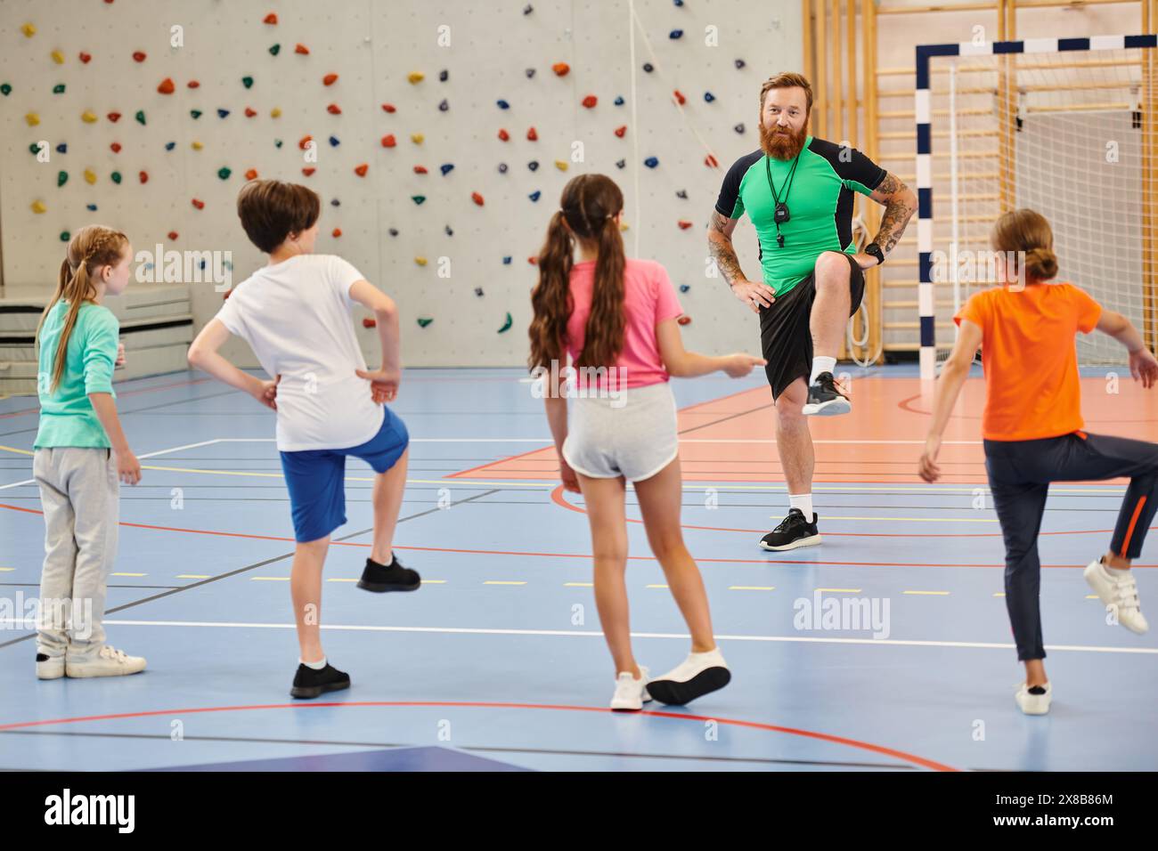 Un groupe diversifié d'étudiants se tient joyeusement sur un sol de gymnastique tout en recevant les conseils de leur professeur dans un cadre de classe lumineux. Banque D'Images