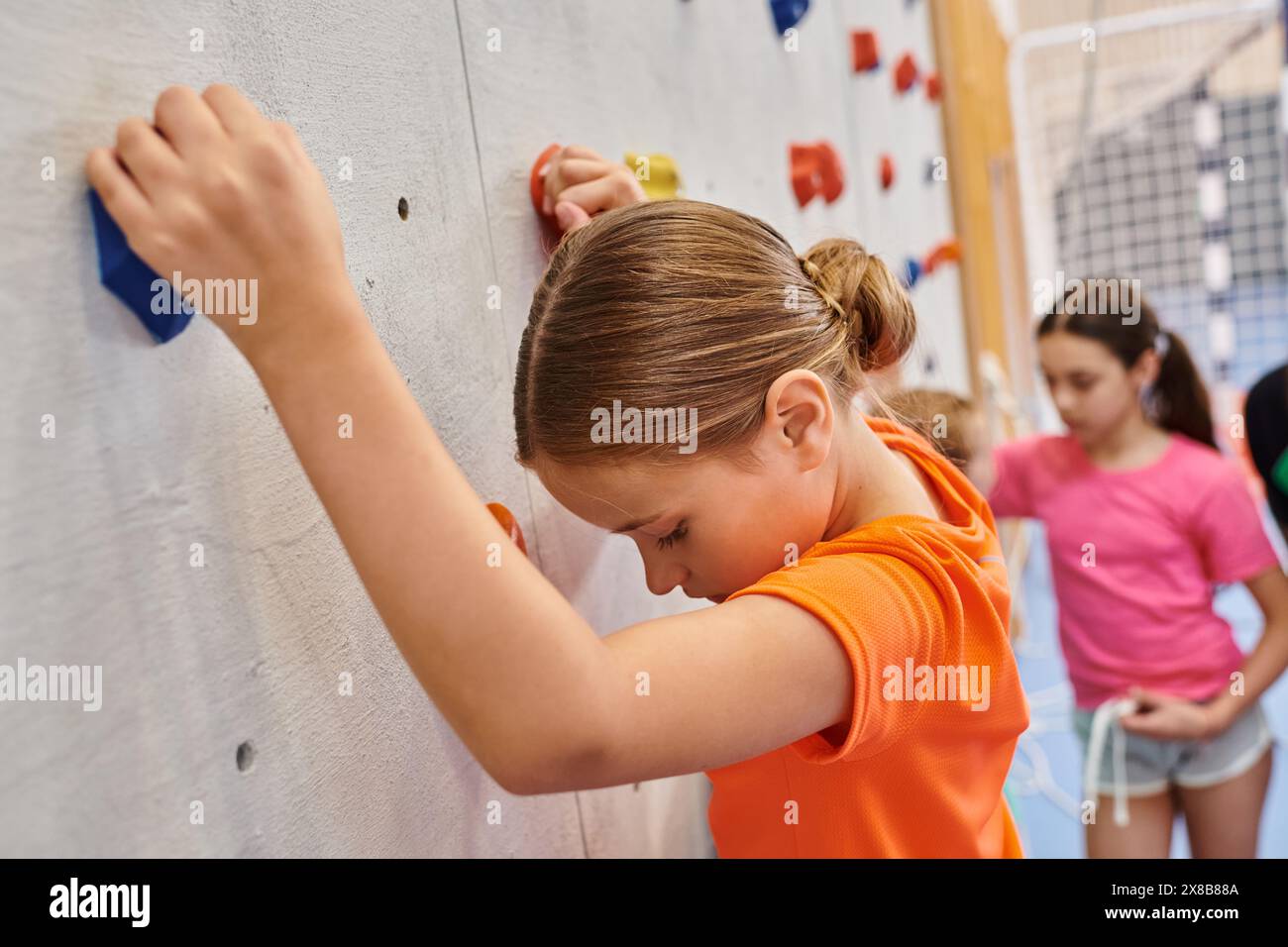 Un groupe diversifié de jeunes filles se tiennent côte à côte, grimpant un mur Banque D'Images