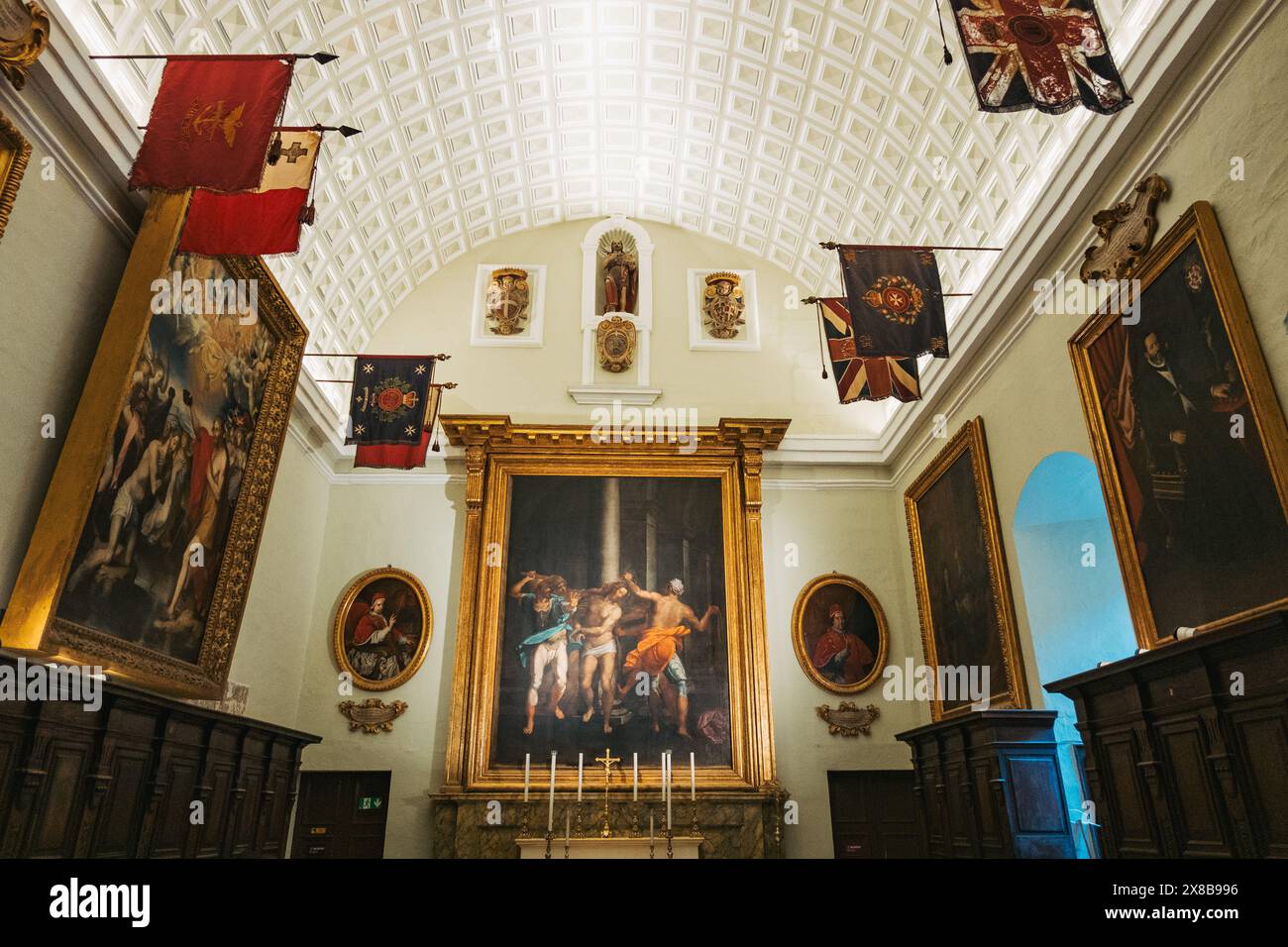 Une salle avec un plafond voûté et des détails ornés présentant une collection de peintures encadrées et de drapeaux dans la co-cathédrale Saint-Jean de Malte Banque D'Images