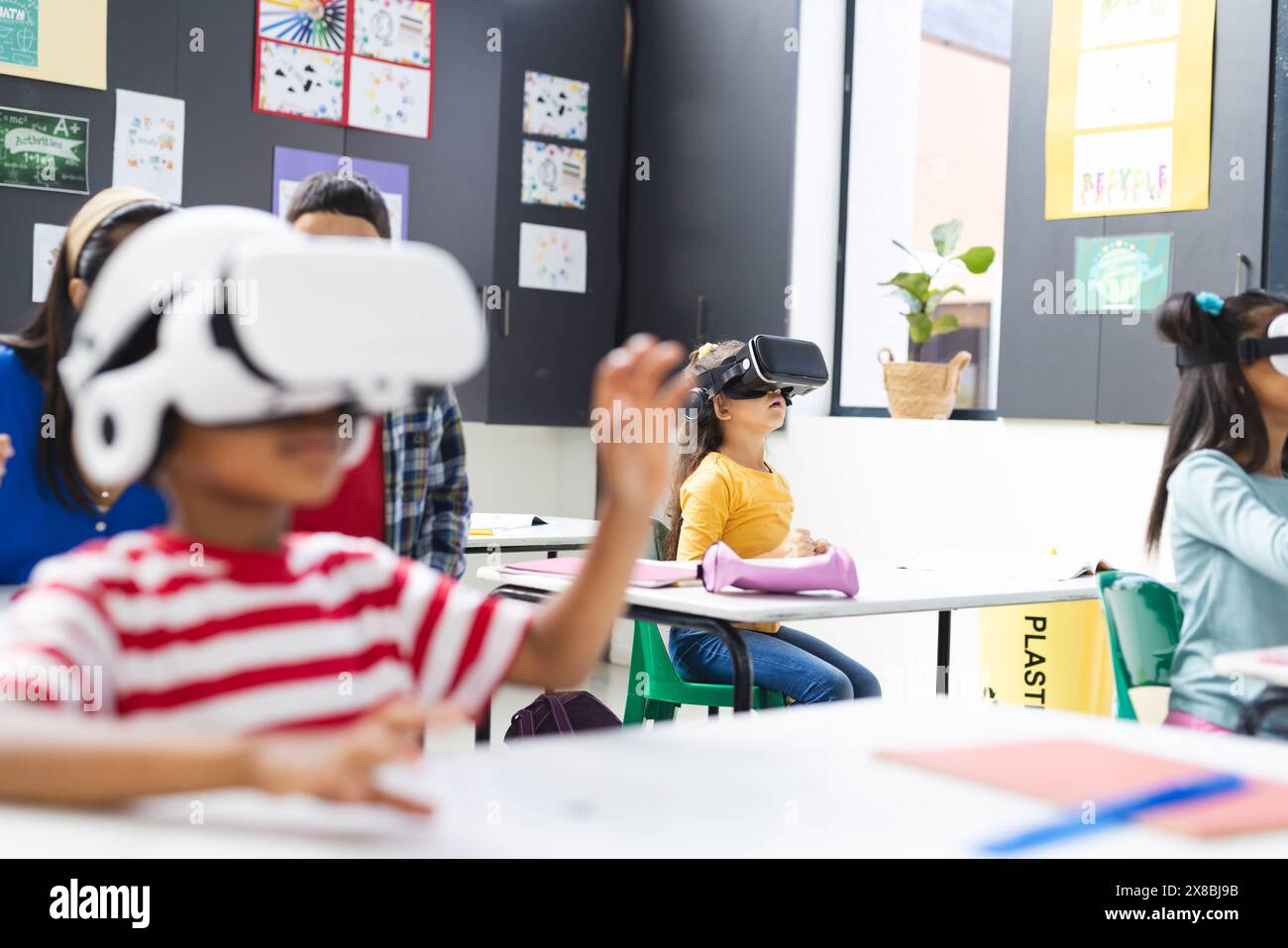 À l'école, un groupe diversifié d'étudiants portant des casques de réalité virtuelle dans la salle de classe, copiez l'espace Banque D'Images