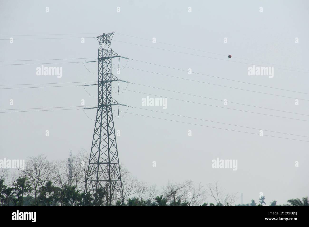 Silhouette d'une tour électrique debout fermement contre le coucher du soleil et le ciel orange Banque D'Images