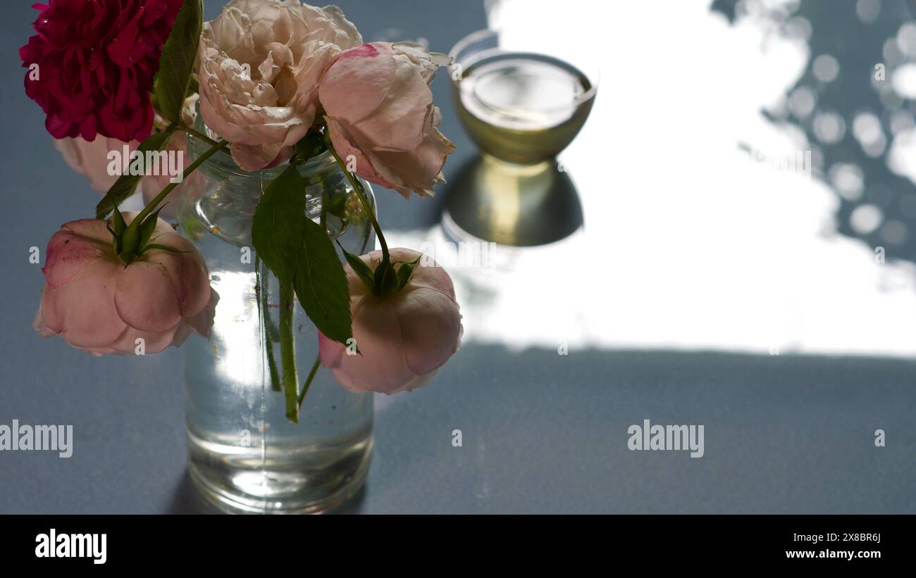Un vase en verre avec des roses et un petit bol de tee-shirt vert. Concept de calme. Banque D'Images