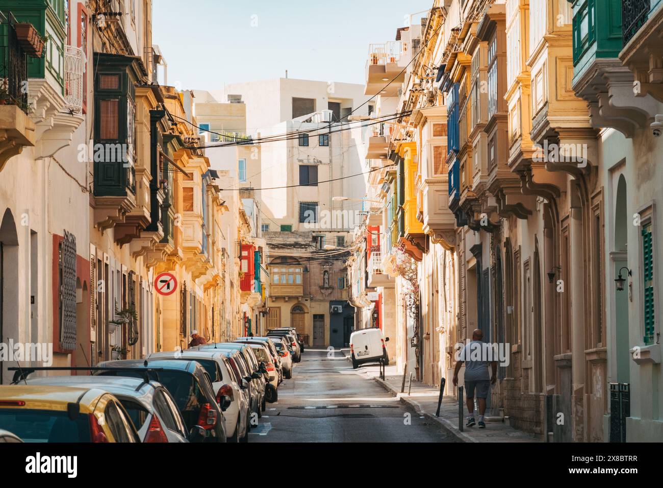 Une rue étroite bordée de maisons en calcaire et de balcons en bois avec fenêtres dans la ville Sliema, Malte Banque D'Images