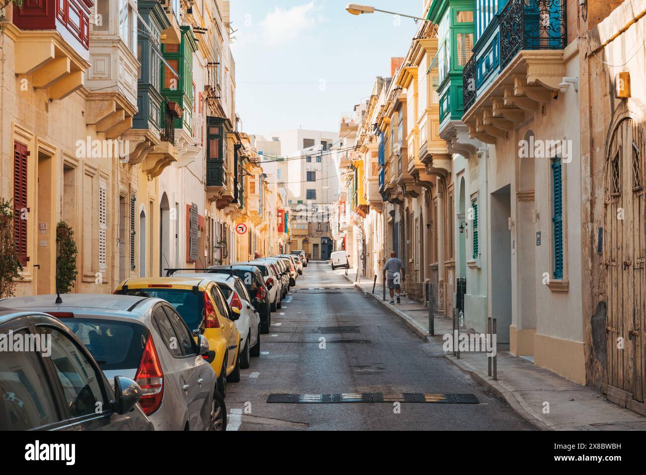 Une rue étroite bordée de maisons en calcaire et de balcons en bois avec fenêtres dans la ville Sliema, Malte Banque D'Images