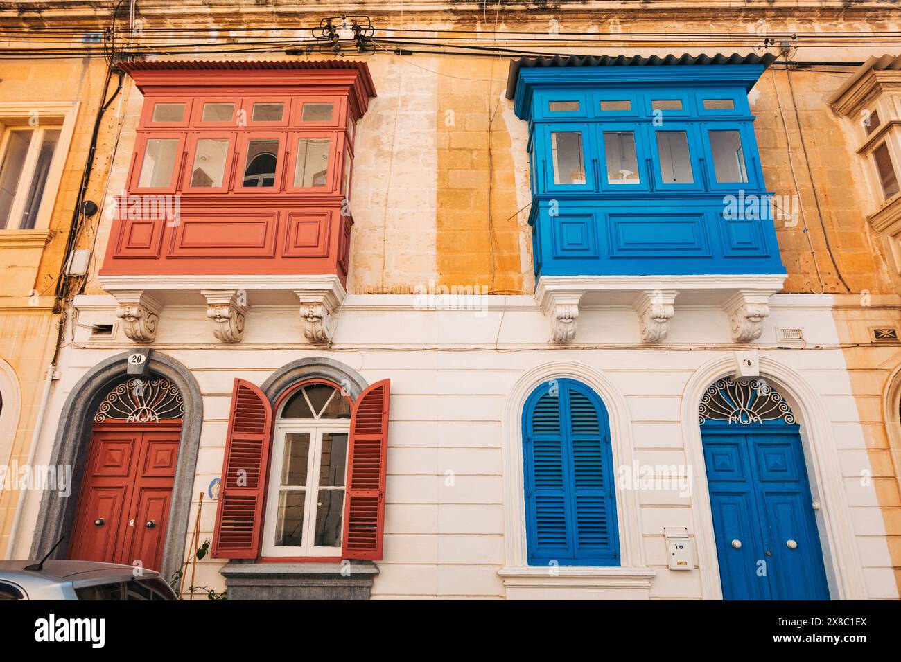 Portes voûtées peintes de couleurs vives et gallarija (fenêtre de balcon en bois) sur une maison en calcaire dans la ville de Sliema, Malte Banque D'Images