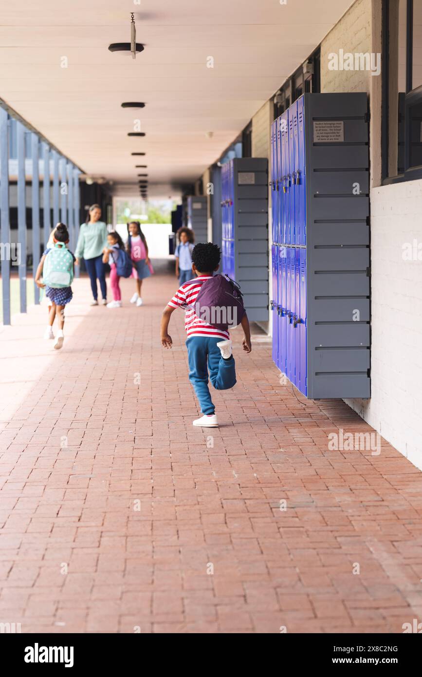 À l'école, des enfants divers marchent dans le couloir avec des casiers avec un espace de copie à l'extérieur Banque D'Images