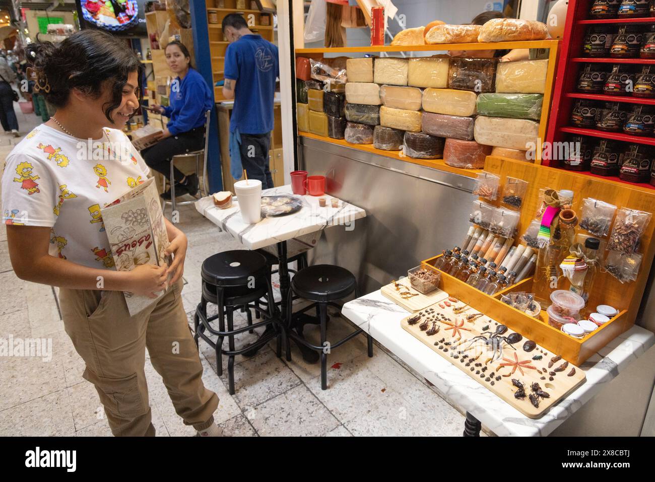 Jeune femme regardant le menu dans un café vendant des araignées, des scorpions et des insectes comme nourriture, marché intérieur de San Juan ; Mexico, Mexique Banque D'Images