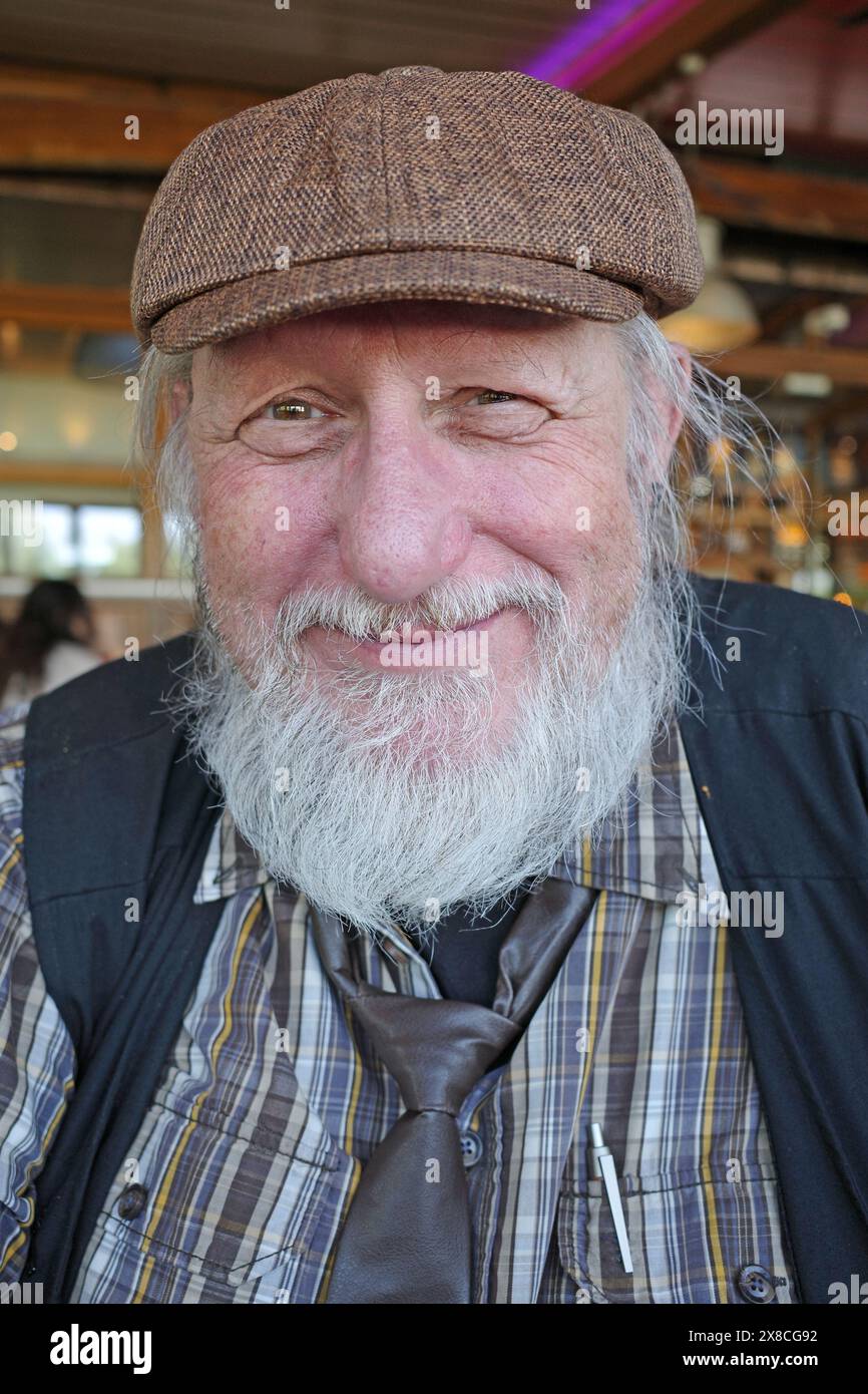Homme senior amical avec un bonnet plat, cravate et barbe Banque D'Images